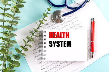 Health system phrase on notepad with stethoscope, medical charts and red pen on blue background