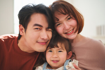 Fototapeta premium Asian parents father and mother smiling with daughter in a portrait at home, showing family love, togetherness, and happy lifestyle moment.