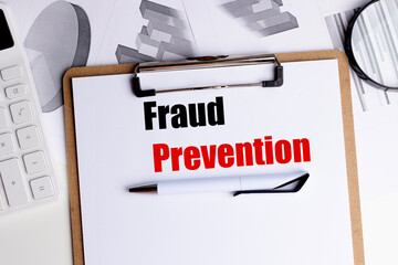 Fraud prevention text on clipboard with pen, calculator and financial documents in office setting