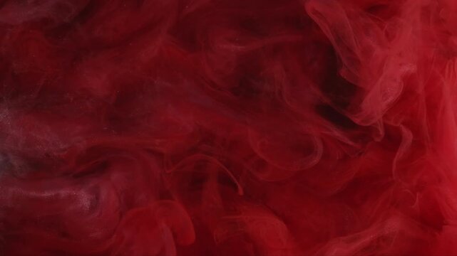 Paint background. Color water. Defocused pink red crimson glitter swirling flow chemical flame spreading on abstract dark black art.