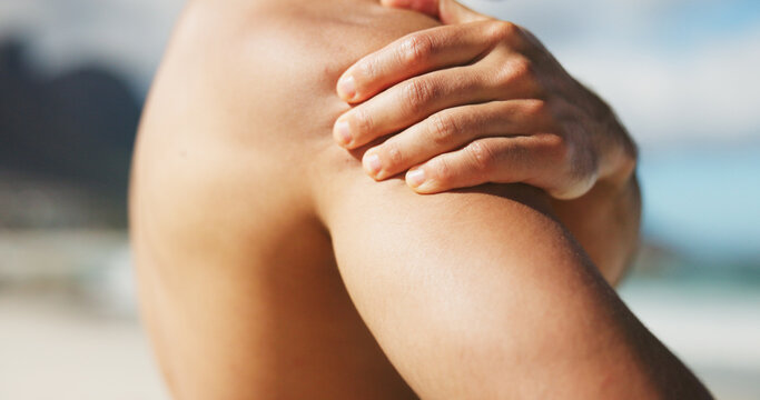 Hand, shoulder and pain at beach with tension, inflammation or stiff joint with fibromyalgia. Person, topless with pressure or spasm of muscle ache, injury or body burnout with cramps outdoor