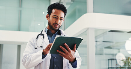 Man, surgeon and reading with tablet in hospital for research, medical report and confirm surgery. Male doctor, digital and review website for Telehealth, healthcare results and treatment information