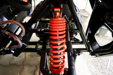 Detailed view of clean red shock absorber spring suspension system under vehicle chassis...