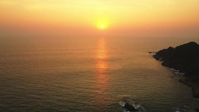 Beautiful sunset over the Arabian Sea, with the sun dipping below the horizon and warm golden light spreading across calm waters.