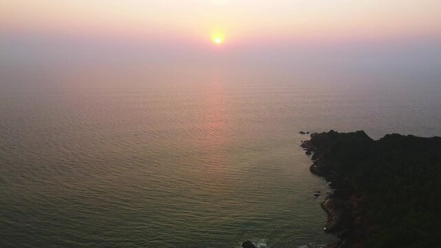 Beautiful sunset over the Arabian Sea, with the sun dipping below the horizon and warm golden light spreading across calm waters.