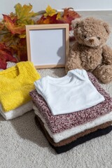 Pregnancy baby coming announcement template with a square wooden frame mockup, warm baby overalls, a bear, and autumn leaves