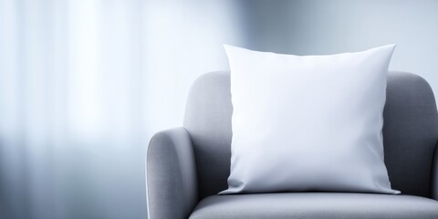 Blank white square cushion mockup on a grey armchair in a living room interior with soft ambient lighting for product display and comfortable home design copy space