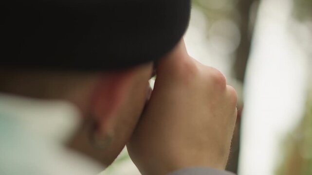traveler peers through monocular into forest, close profile and beanie visible with steady hand grip on tube, focused observation and quiet scouting action, scout or birdwatcher role in green