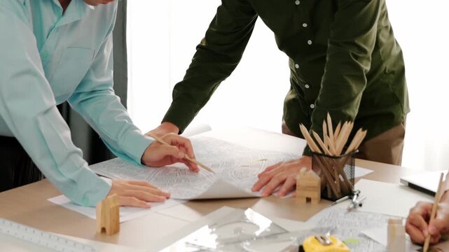 Professional engineer measuring the blueprint. Professional engineer working architectural project at studio on a table with yellow helmet and architectural equipment scatter around. Delineation.