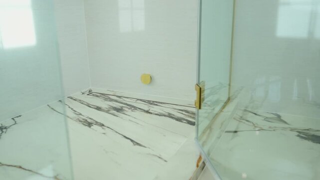 pov a modern glass shower enclosure with open glass door and polished marble bathroom floor. luxury interior design, clean architecture, and elegant bathroom renovation.