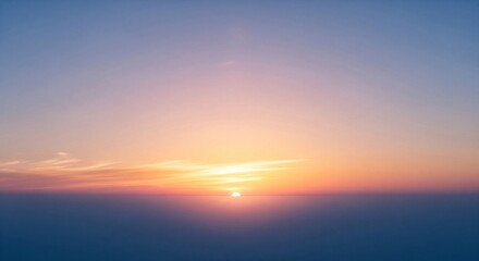 Fototapeta premium A serene and vibrant sunrise painting the sky with warm hues of orange and pink over a hazy, distant horizon.