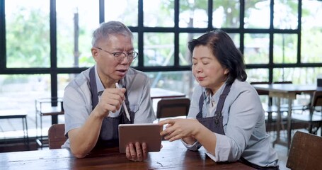 Elderly asian couple cafe owner discussing restaurant business plan reviewing tablet data teamwork partnership communication cooperation lifestyle entrepreneur husband wife collaboration management - Powered by Adobe
