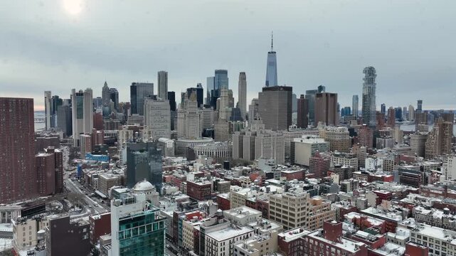 Snow flurries flying across Manhattan skyline in winter, revealing dense high-rise architecture, cold gray skies and cinematic urban atmosphere over New York City. Aerial wide shot.