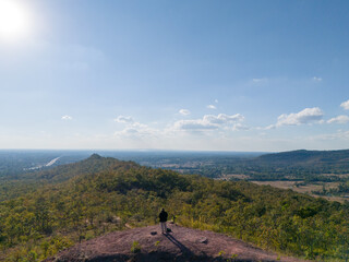 Back view of a man taking photos at a 360 degree viewpoint in Phu Pha Wua Forest Park, Kalasin Province, Thailand, surrounded by natural landscape and scenic mountain views.