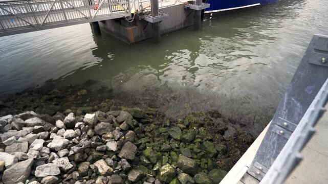 Rocky Shoreline Utilizing Riprap Of Large Irregular Rocks To Protect Shoreline In NYC Next To A Ferry