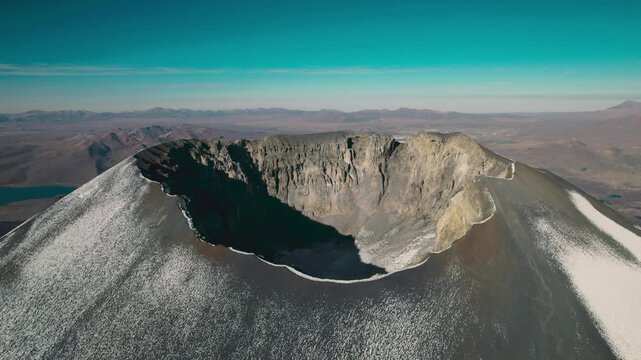 Breathtaking drone view looking into the summit crater of Parinacota Volcano. Jagged volcanic rim and vast Altiplano landscape in the Sajama National Park region.