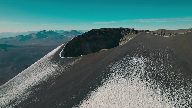 Orbiting drone shot looking into the summit crater of Parinacota Volcano. Rugged rim and expansive Altiplano landscape in Sajama National Park.