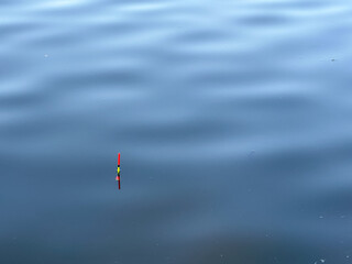 Fishing float in calm blue lake water. © SashaMagic