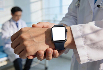 A person in a white lab coat with a stethoscope checks the time on a smartwatch, with a blank white screen, while seated in the background is another individual wearing glasses and a lab coat.