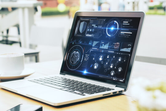 Open laptop on a wooden desk displaying futuristic analytics dashboard with user interface widgets, data charts, circular HUD elements and digital business intelligence metrics

 - Powered by Adobe