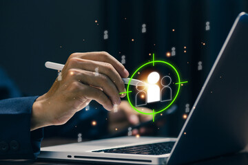 Businessman using stylus to select target audience icon on laptop, representing customer targeting, market segmentation, digital marketing strategy, audience analysis, and data-driven business growth.