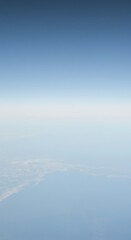 Limitless perspective showing the faint line where the vast, pale blue sky connects with the subtle texture of the distant earth, atmospheric, conceptual, copy space