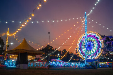 Colorful night carnival with bright lights, ferris wheel, and amusement rides, Festive atmosphere...