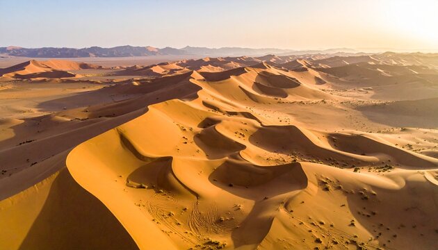 Golden desert dunes ripple across the horizon, bathed in the warm light of sunrise, showcasing the serene and dramatic natural beauty of an arid landscape