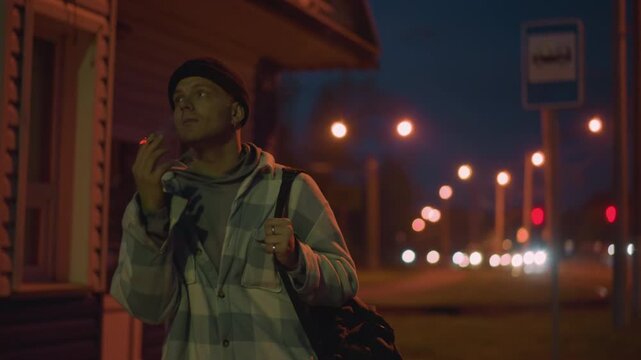 night bus stop black man exhaling smoke under streetlights, holding cigarette and backpack, watching blurred traffic lights, frames show ritual inhale, thoughtful glance, steady posture, roles include