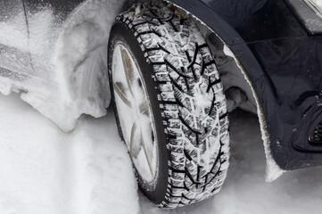 A car equipped with a winter tire driving in deep snow. A snow tire in deep snow