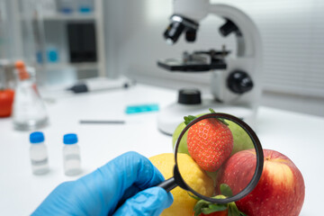 Scientist use magnifying glass to check physical occur from chemical on fruit and vegetable residues in laboratory. inspect the concentration of chemical residues, standard, find prohibited substances