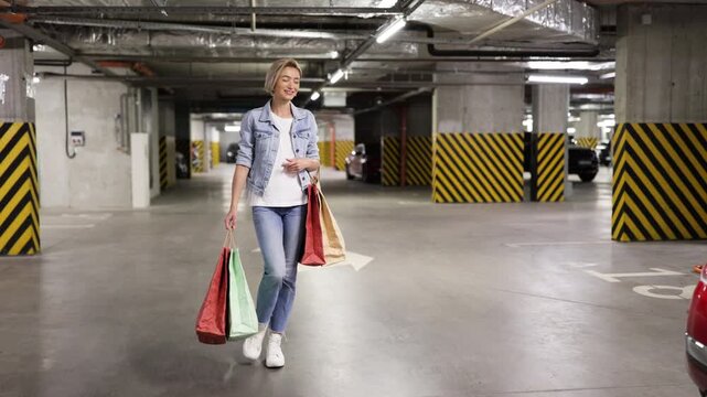A woman loads shopping bags into the trunk of a red car in an underground parking garage