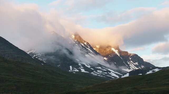 Tindevegen, &Oslash;vre &Aring;rdal, Norway - Low Clouds Drift Across Rugged, Snow-streaked Mountain Peaks Glowing With Soft Light - Static Shot