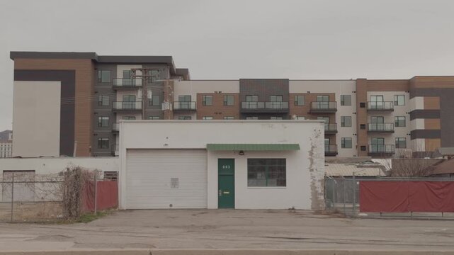 Locked-off shot of a small urban building as a car briefly passes, then the street remains empty