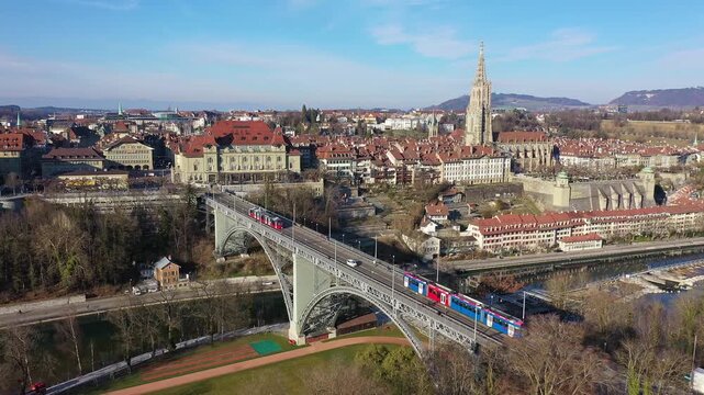 Bern, Switzerland: Aerial drone footage of a tramway on a bridge over the Aar vier toward Bern old town with its cathedrdal in Switzerland capital city. 