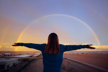 Lucky Woman Enjoying a Rainbow from her Balcony. Hopeful lady enjoying the weather from home looking at the sky
