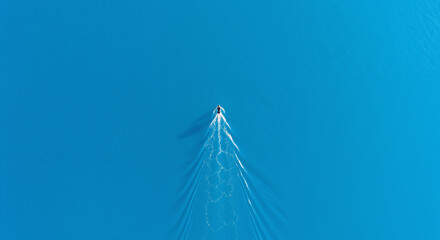 Aerial top view of a lone swimmer swimming through deep blue water, cold exposure and travel concept.
