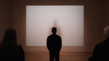 Silhouetted figure in gallery gazes at blank canvas, exploring c