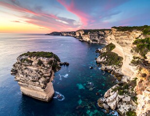 Stunning coastal scene with dramatic cliffs, a solitary rock formation, and vibrant sunset colors