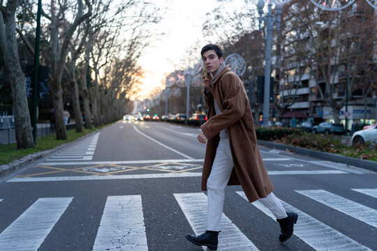 Young man crossing city street talking on phone - Powered by Adobe