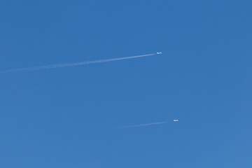 twin engined jet liner aircraft with contrails, in flight at high altitude, clear blue sky