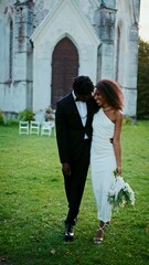 Fototapeta premium The bride and groom embrace and smile at each other walking near the church