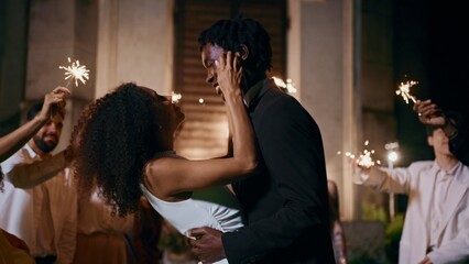 The bride and groom dance surrounded by guests with sparklers in their hands