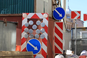 Blue road signs with white arrows and red and white poles with the direction of movement to the right