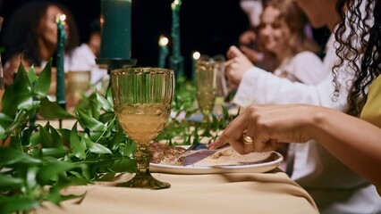 Guests eat and talk while sitting at a festive table outdoors at night