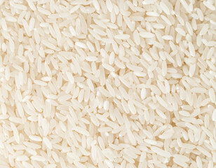 Full frame close-up of uncooked white rice grains forming a dense, uniform texture. Rice photographed from above with visible grain shape and surface.