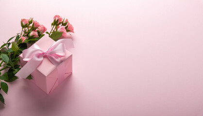 Gift, present box decorated with pink ribbon bow, rose flowers on pink background. Valentine's day, 14 February, birthday, 8 march women's day gift. Love and romance.