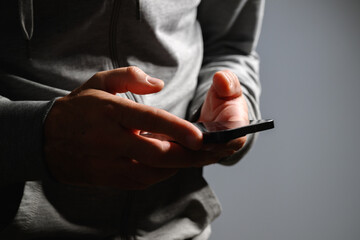 Closeup of male hands using smartphone in low key light, browsing and working on touchscreen device at night.