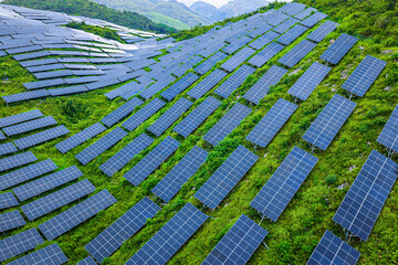 High angle view of numerous solar panels installed on a lush green mountain slope for sustainable...