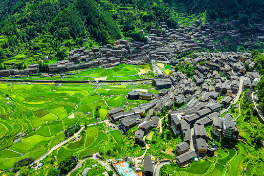 High angle aerial view of traditional wooden houses and lush green terraced rice fields in Xijiang Qianhu Miao Village, Guizhou, China.